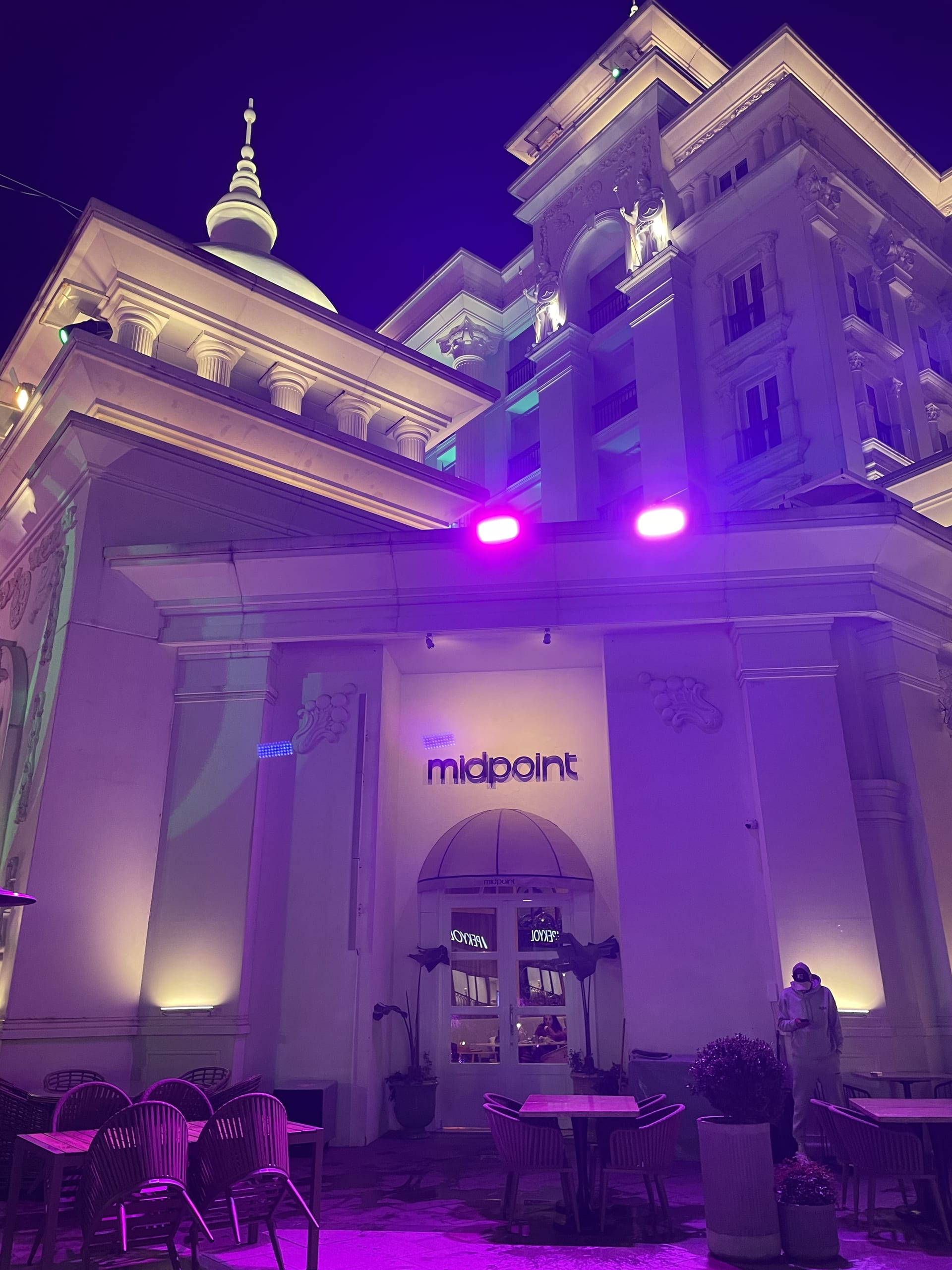 The Midpoint entrance and outdoor tables are illuminated by purple lights