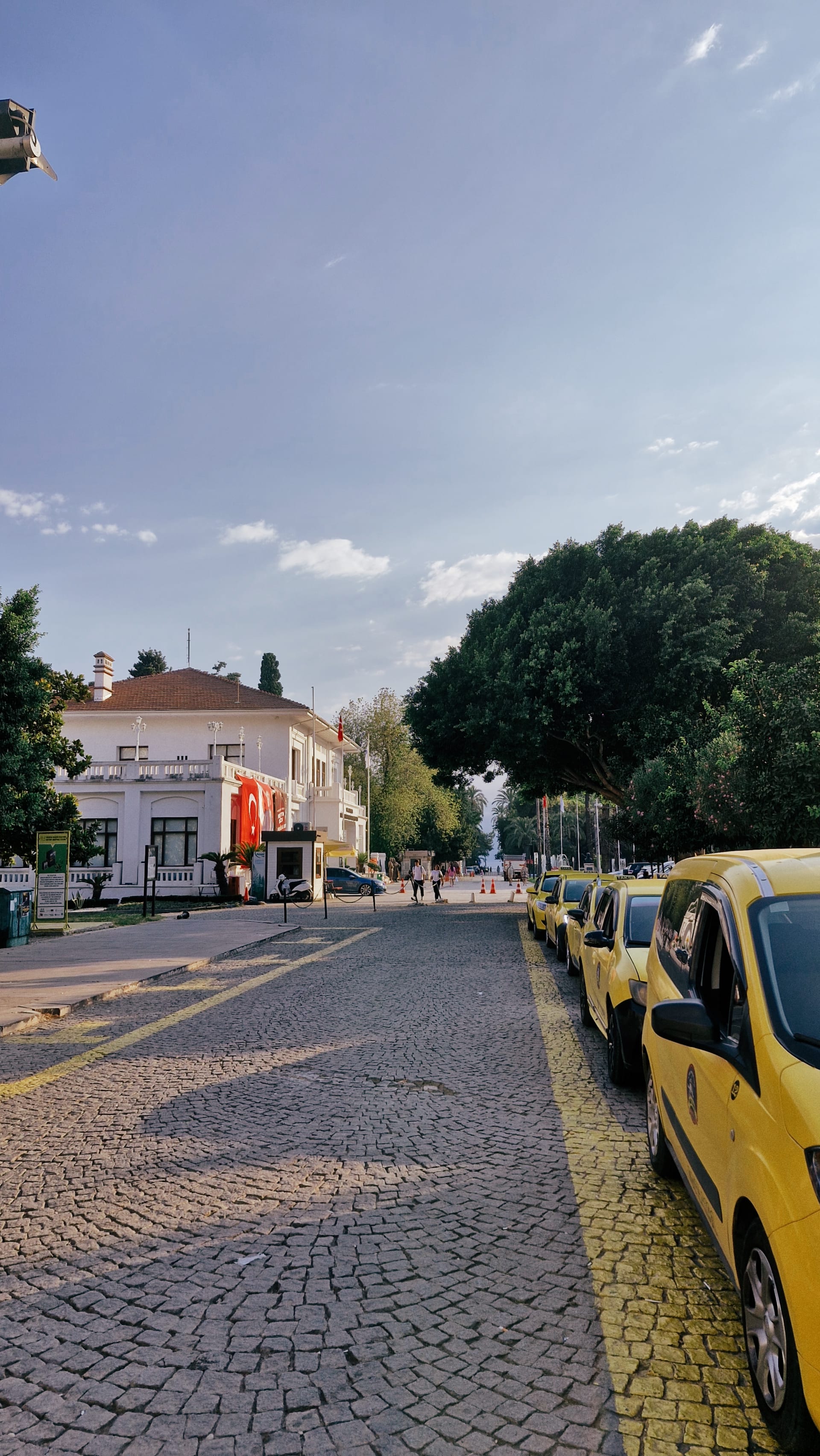 Yellow taxis parked along a cobbled street with low buildings ahead.