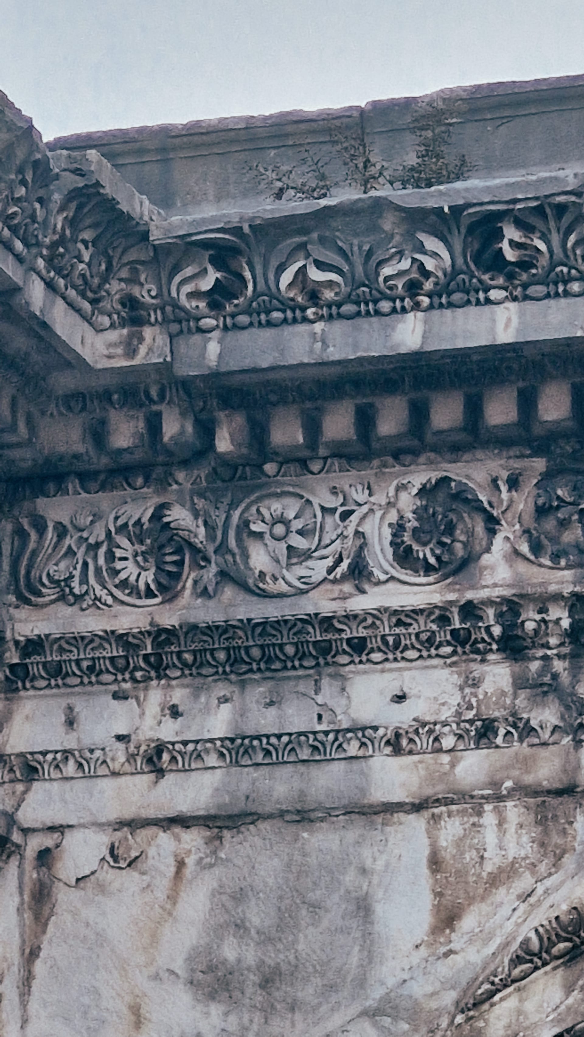 Close view of layered floral and geometric carving above an arch.