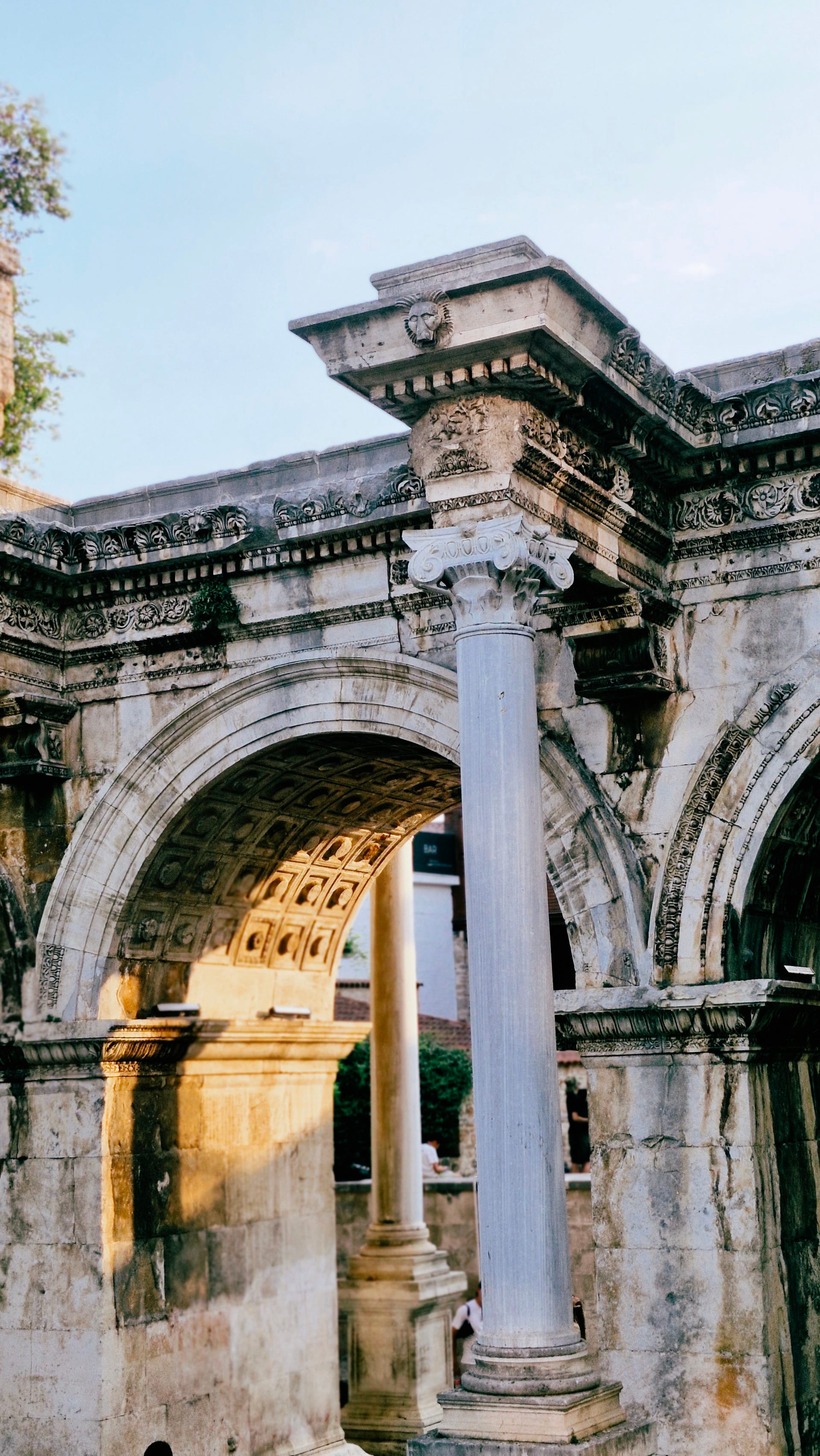 Sunlit arch framed by carved stone bands and a white column.