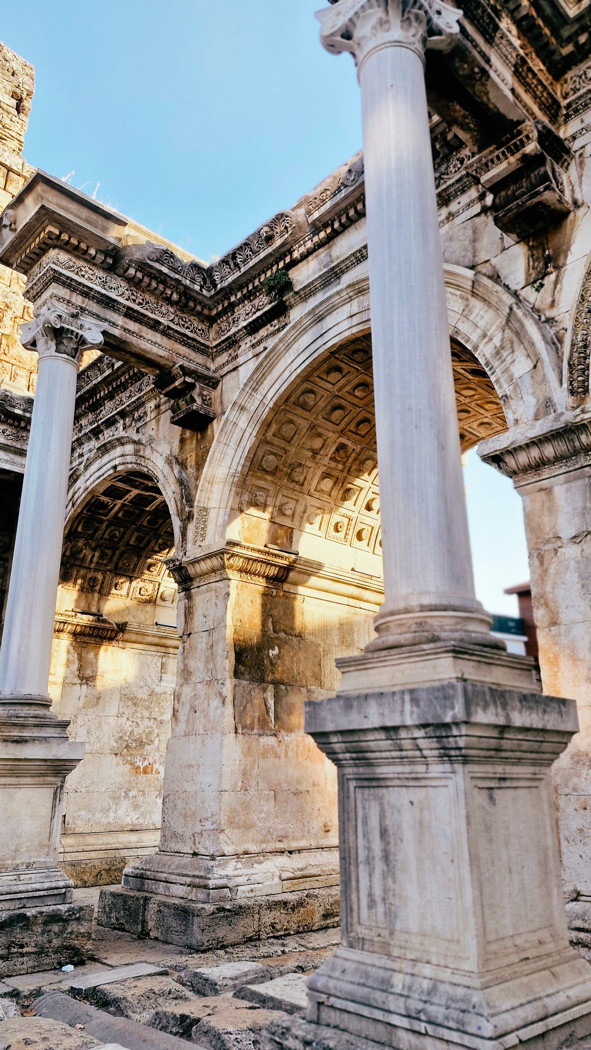 White stone column and deeply carved arch lit by low sunlight.