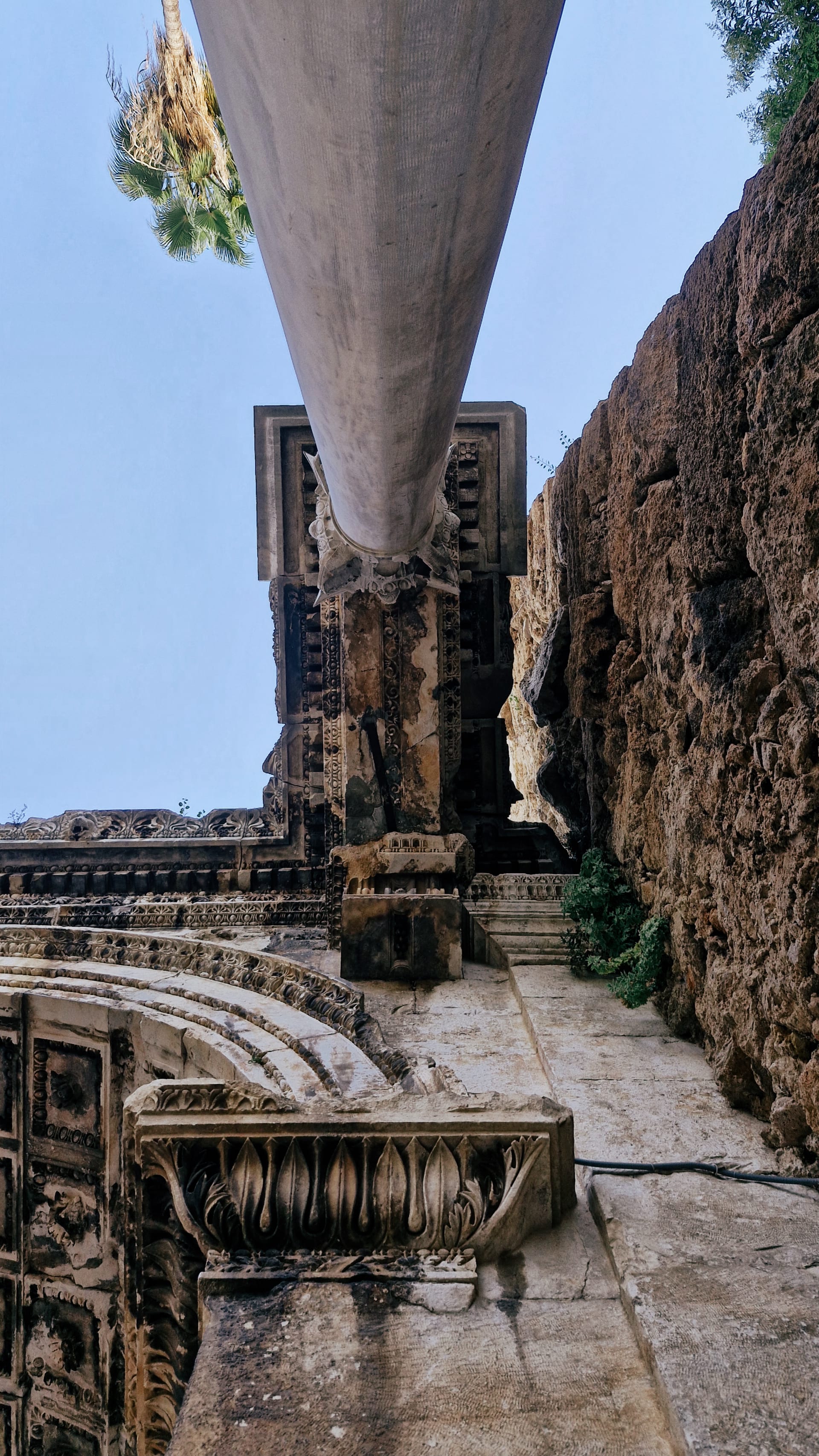 White column seen from below against the tower wall and carved arch.