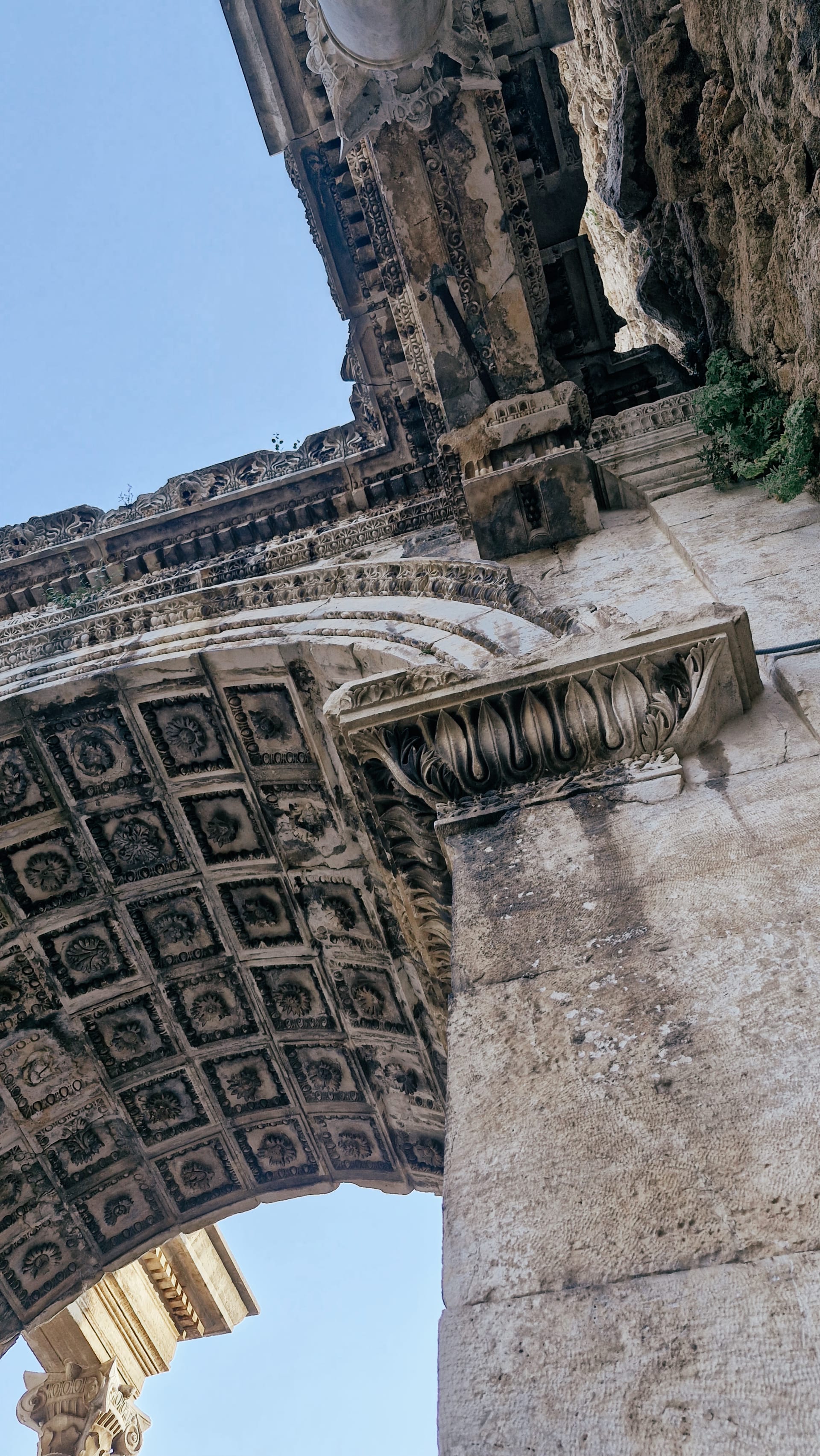 Tilted view beneath a coffered arch with carved stone moulding.