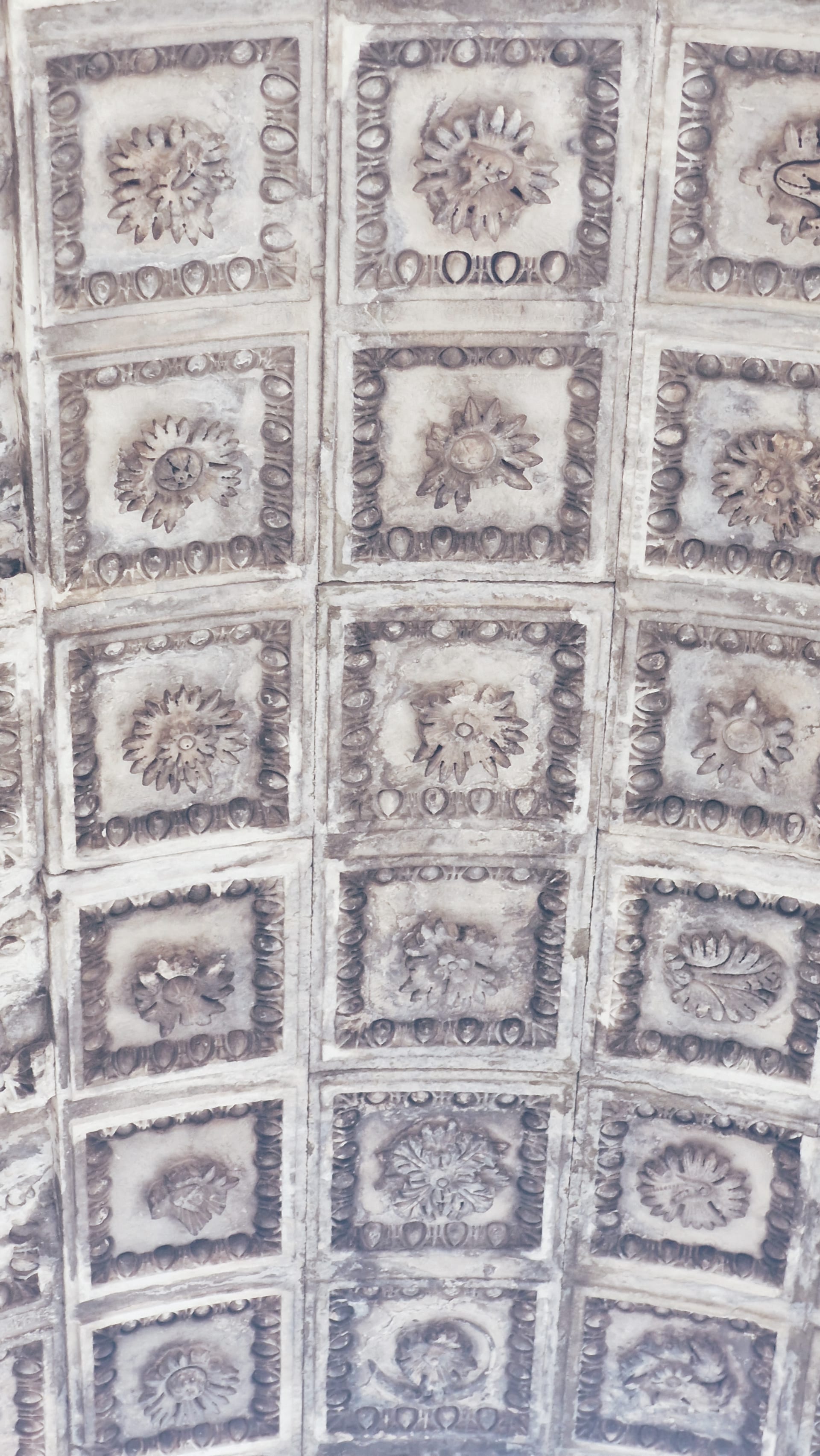 Coffered underside of a stone arch filled with square floral panels.