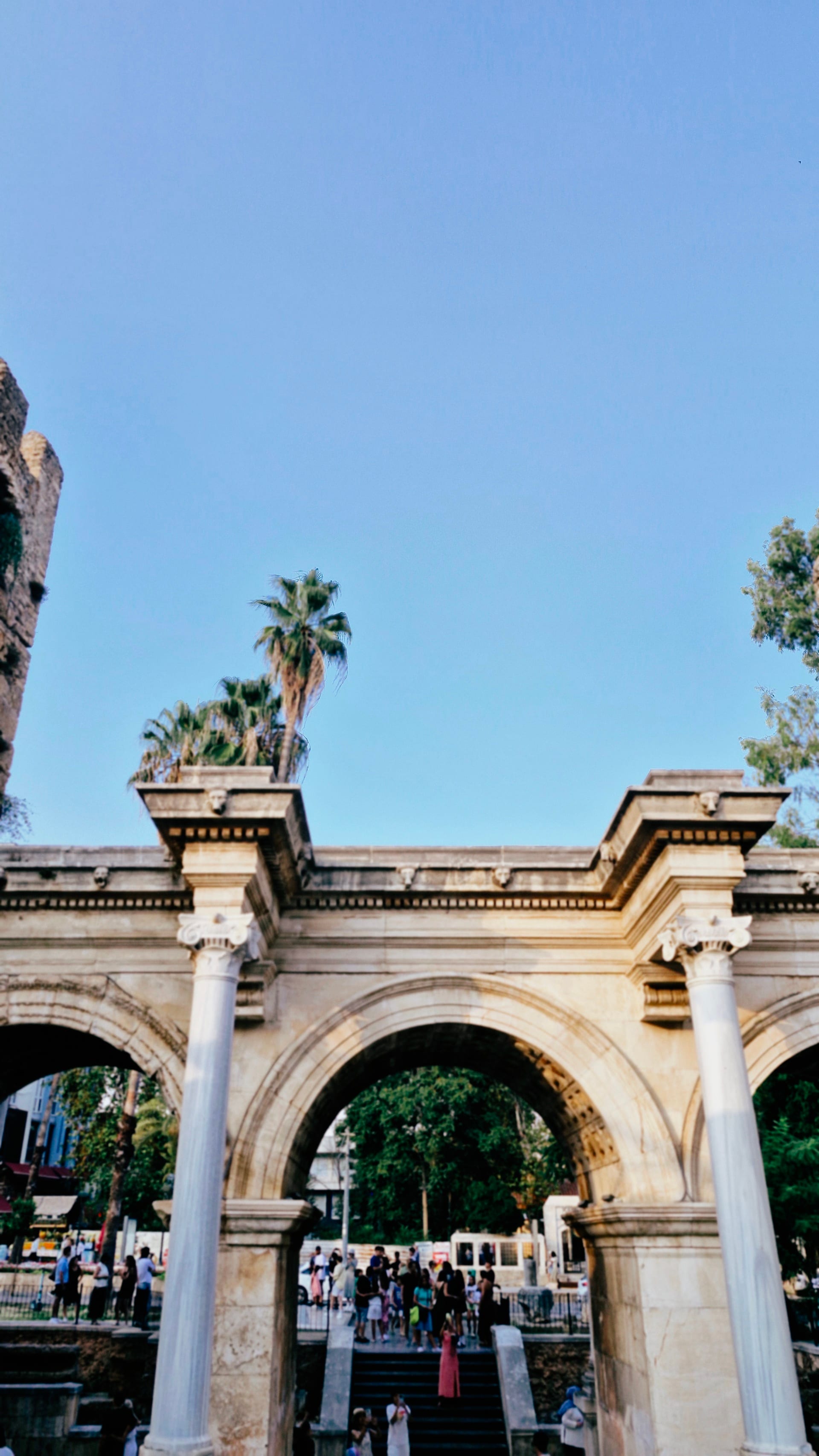 Three arches of Hadrian’s Gate seen from inside Kaleiçi with palm trees beyond.