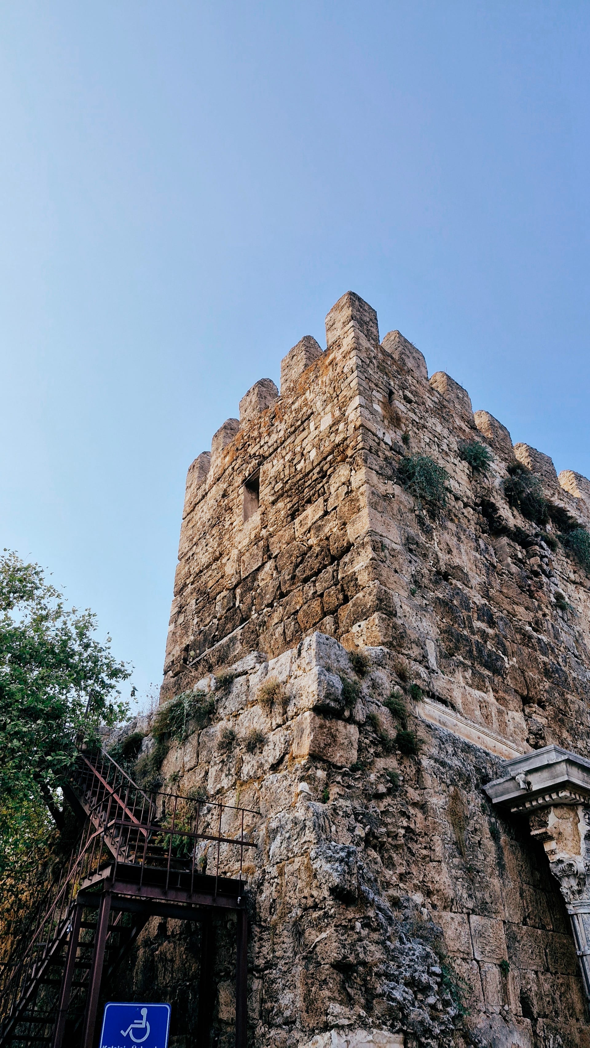 Crenellated stone tower rising against a clear blue sky.
