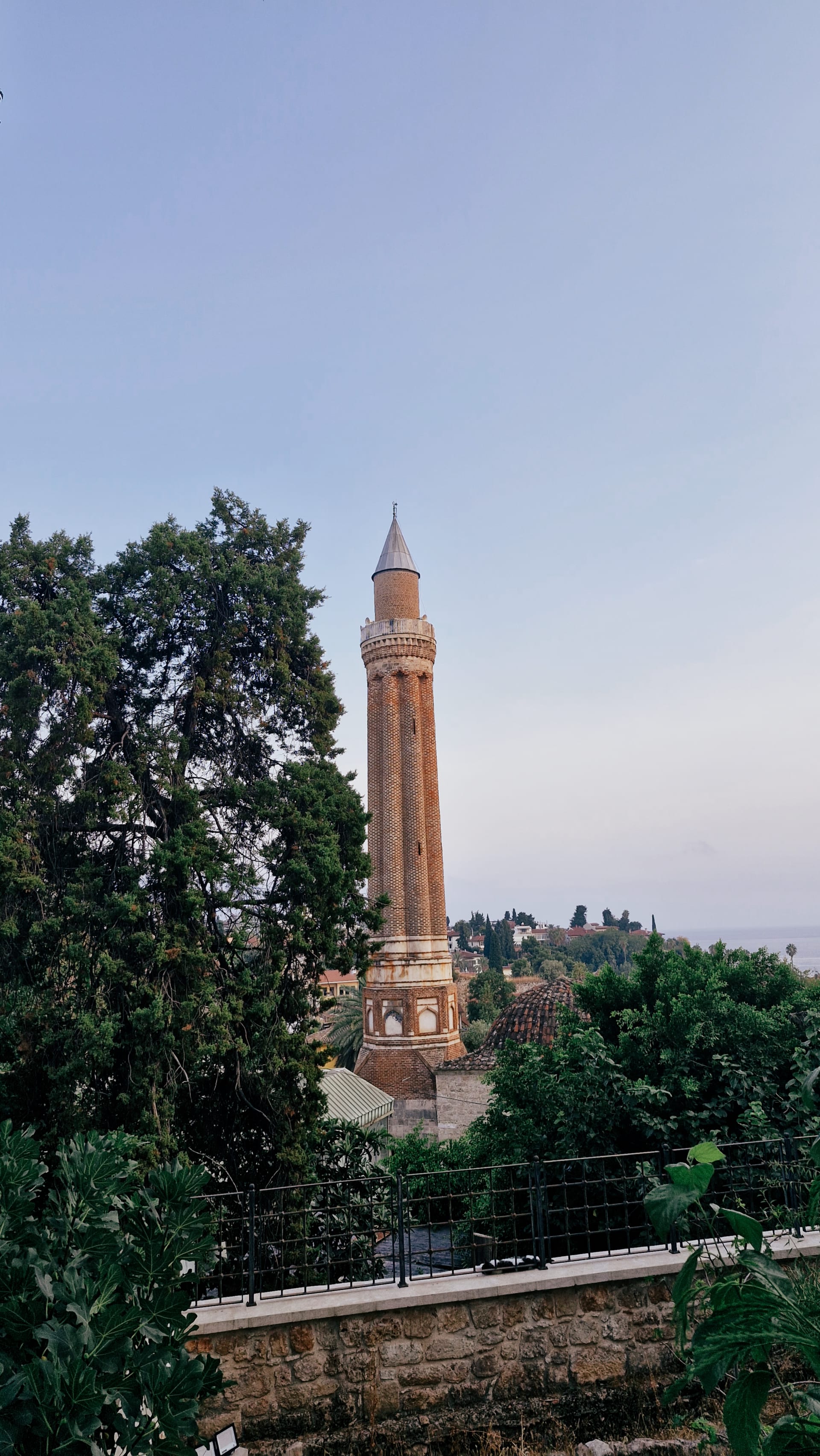Yivli Minaret rising beyond dense trees and red-tiled old-town roofs.