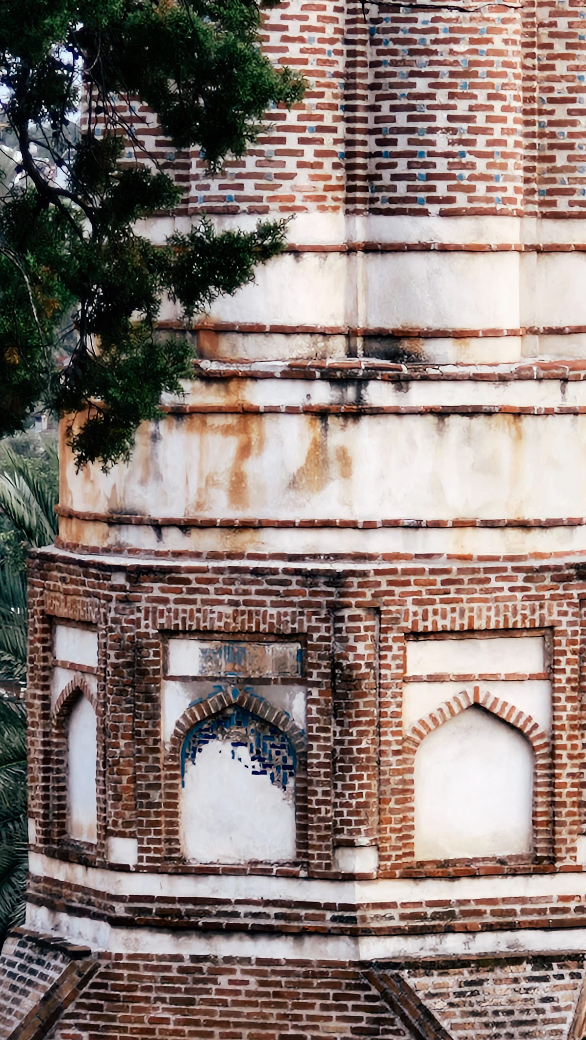Close view of the minaret's brick-and-stone base with pointed recessed panels.