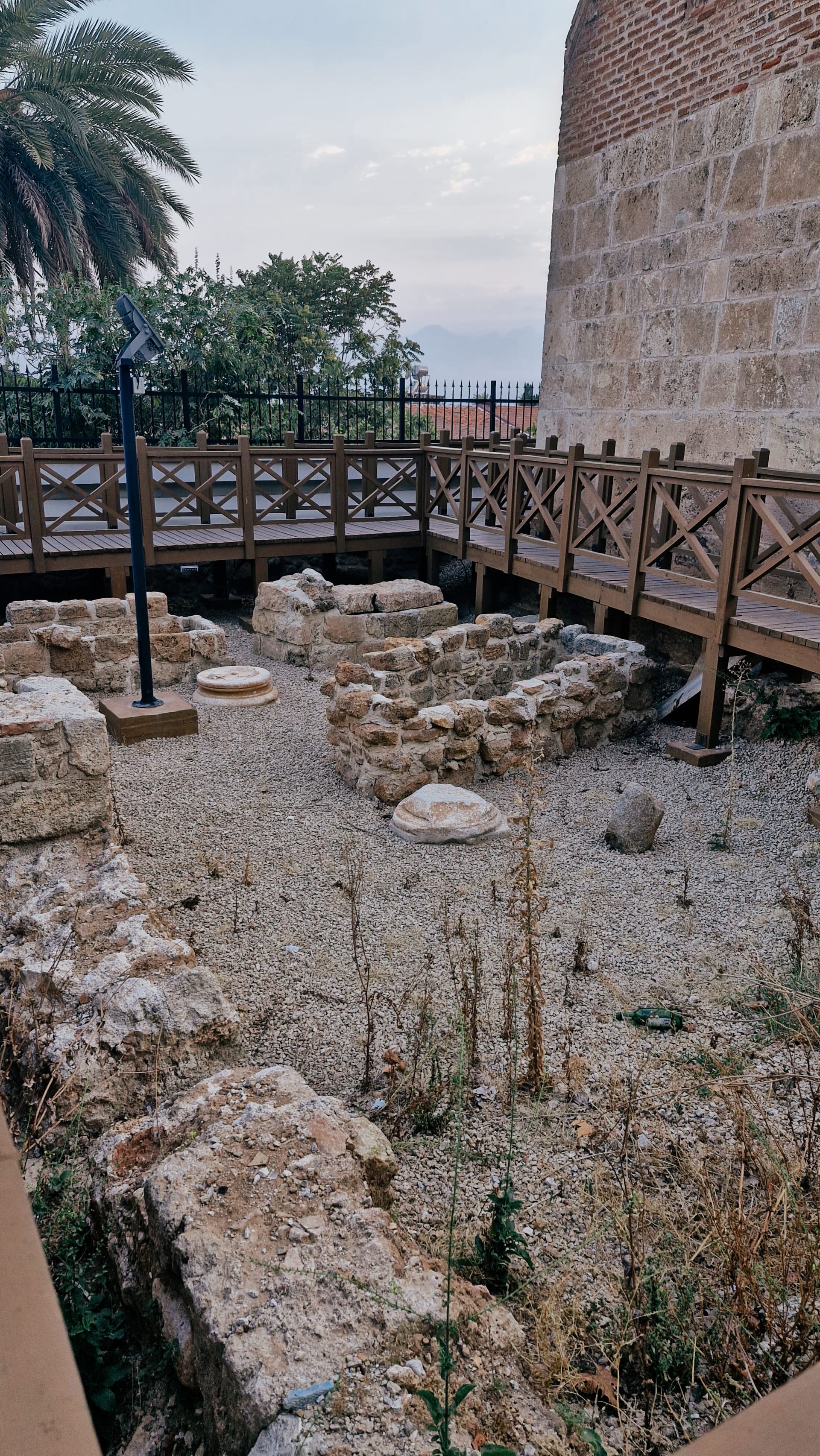 Low stone foundations beside a raised wooden walkway and masonry building.