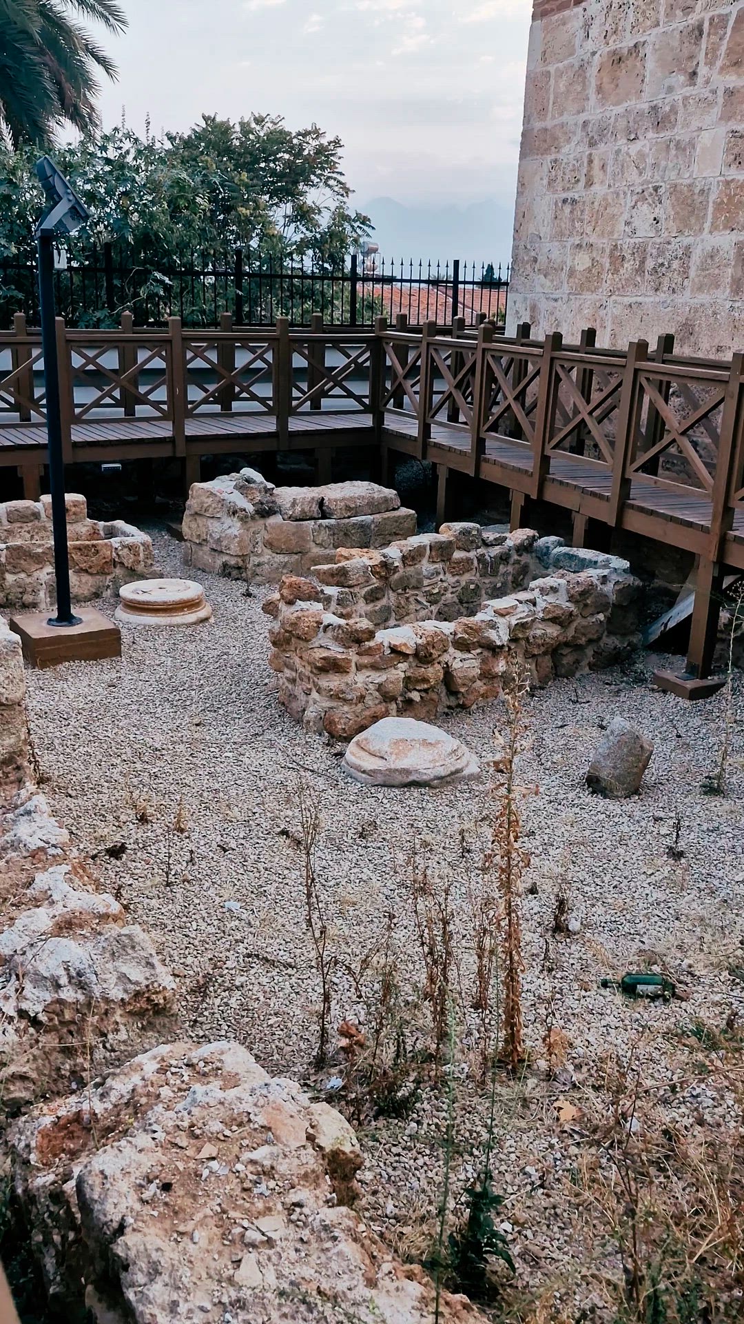 Video crossing low stone foundations and a wooden walkway before tilting toward the minaret.