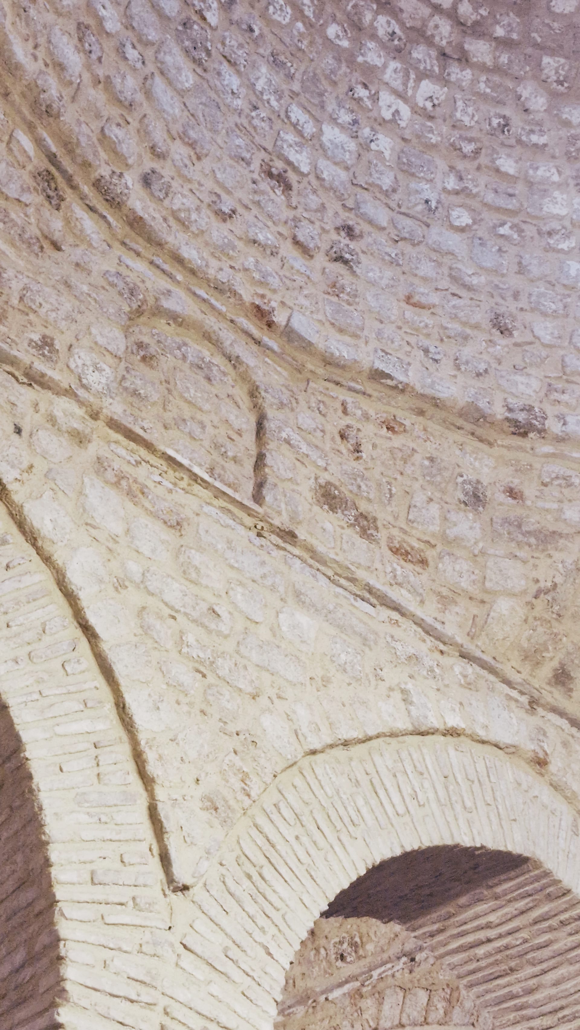 Pale brick vault and pointed arch seen from directly below.