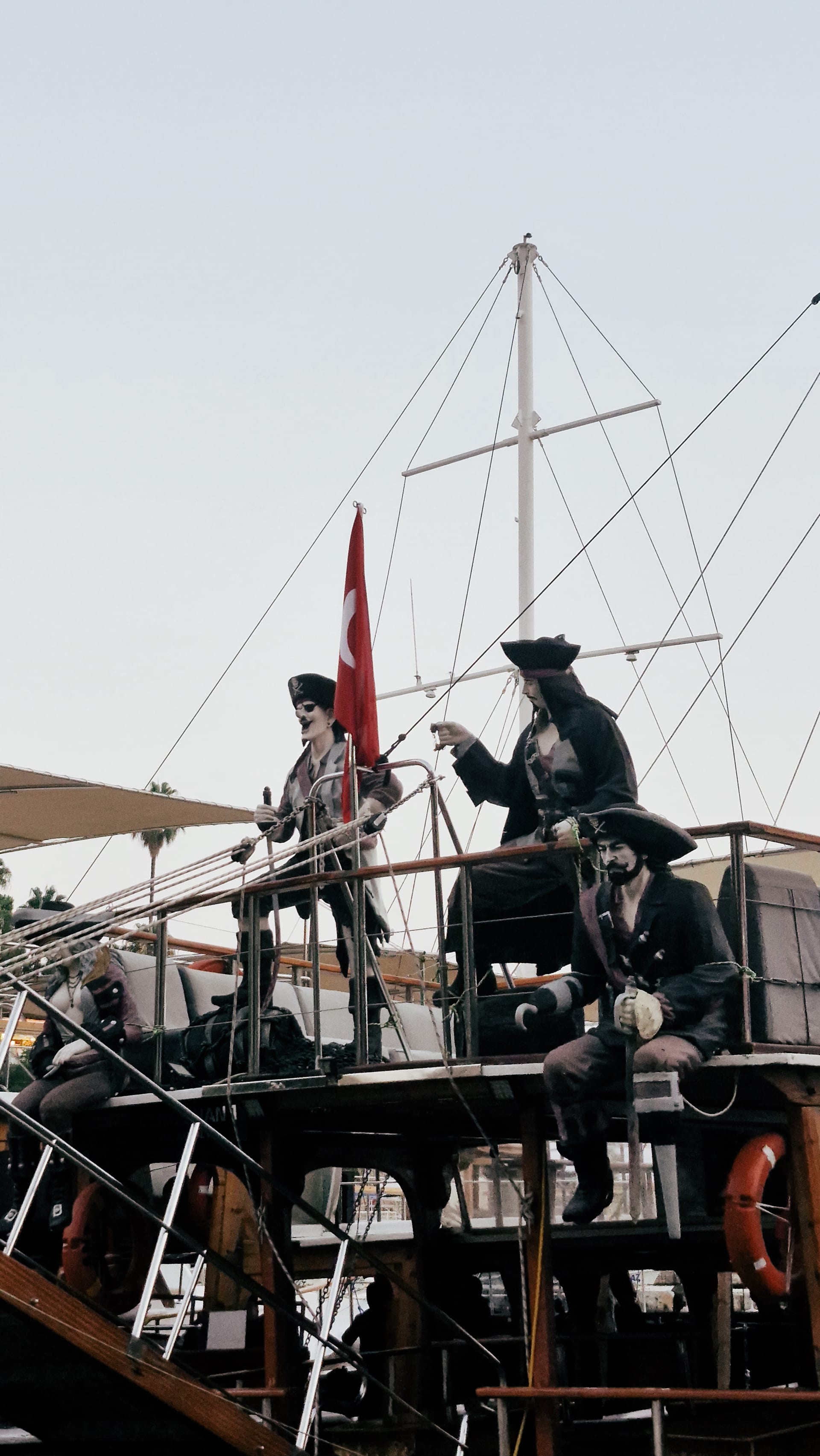 Costumed figures on the upper deck of a tour boat beside a Turkish flag.