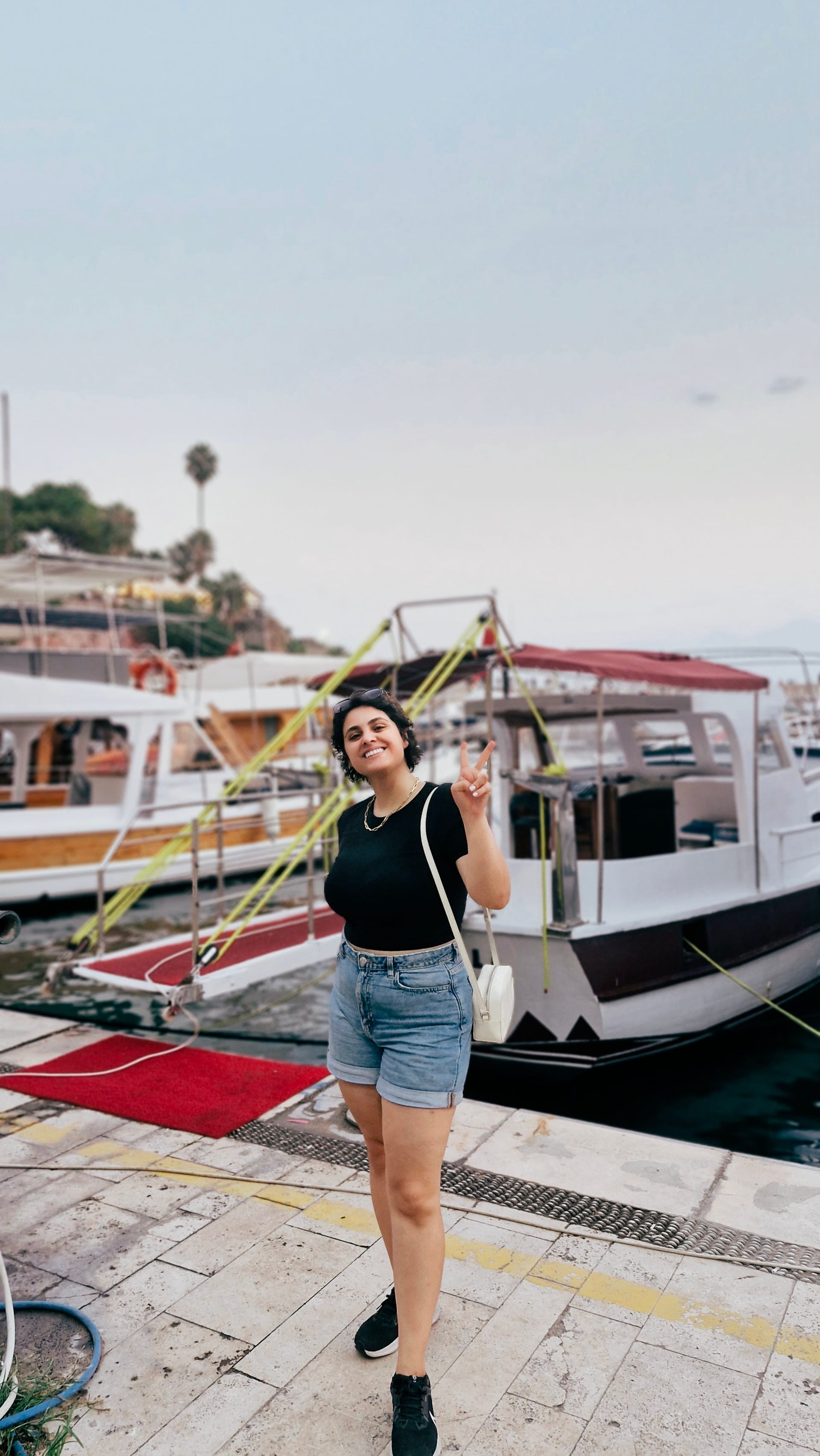 Woman smiling on the quay with small tour boats moored behind her.