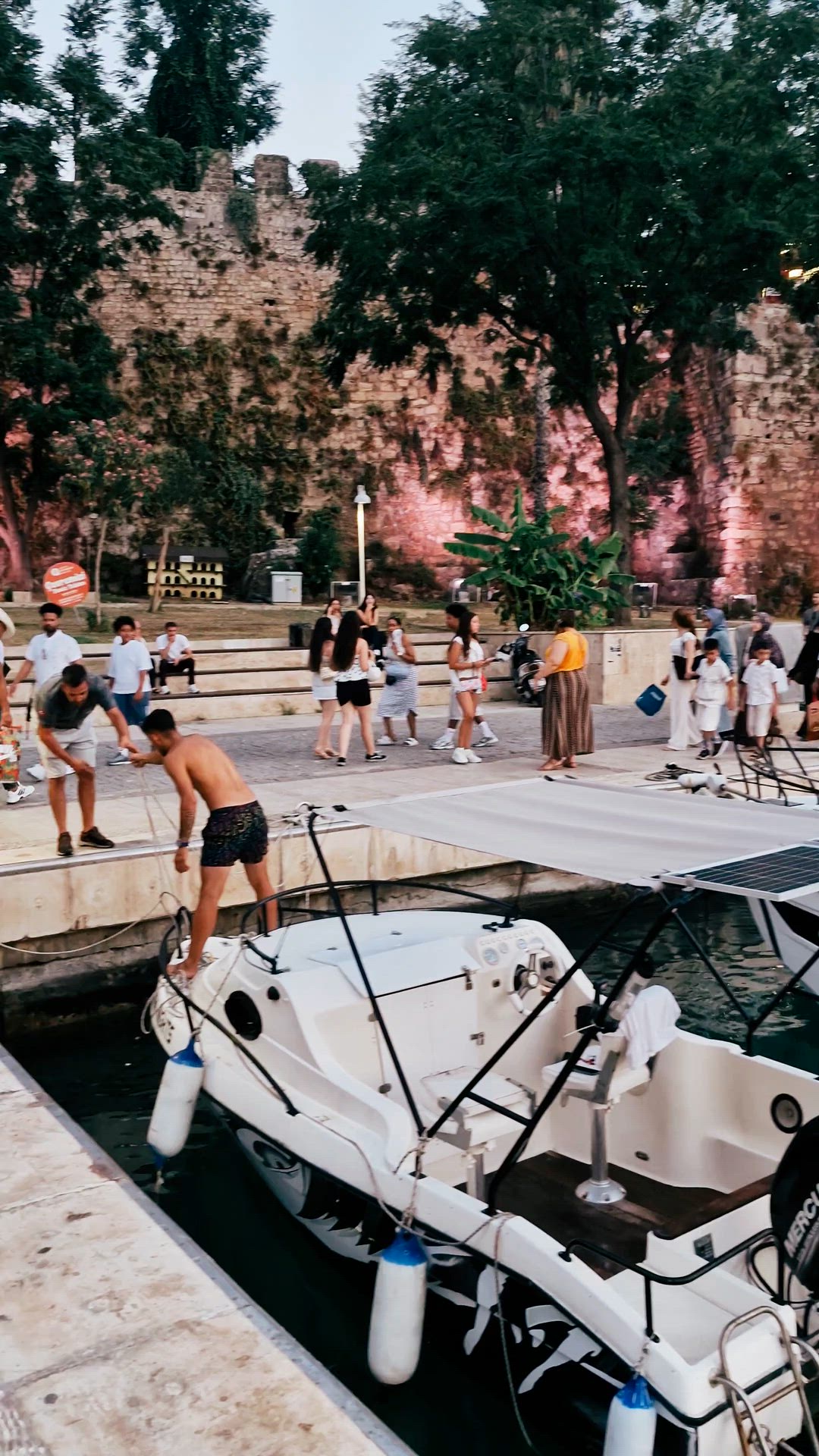Video panning from moored boats across rippling water towards the harbor cliffs.