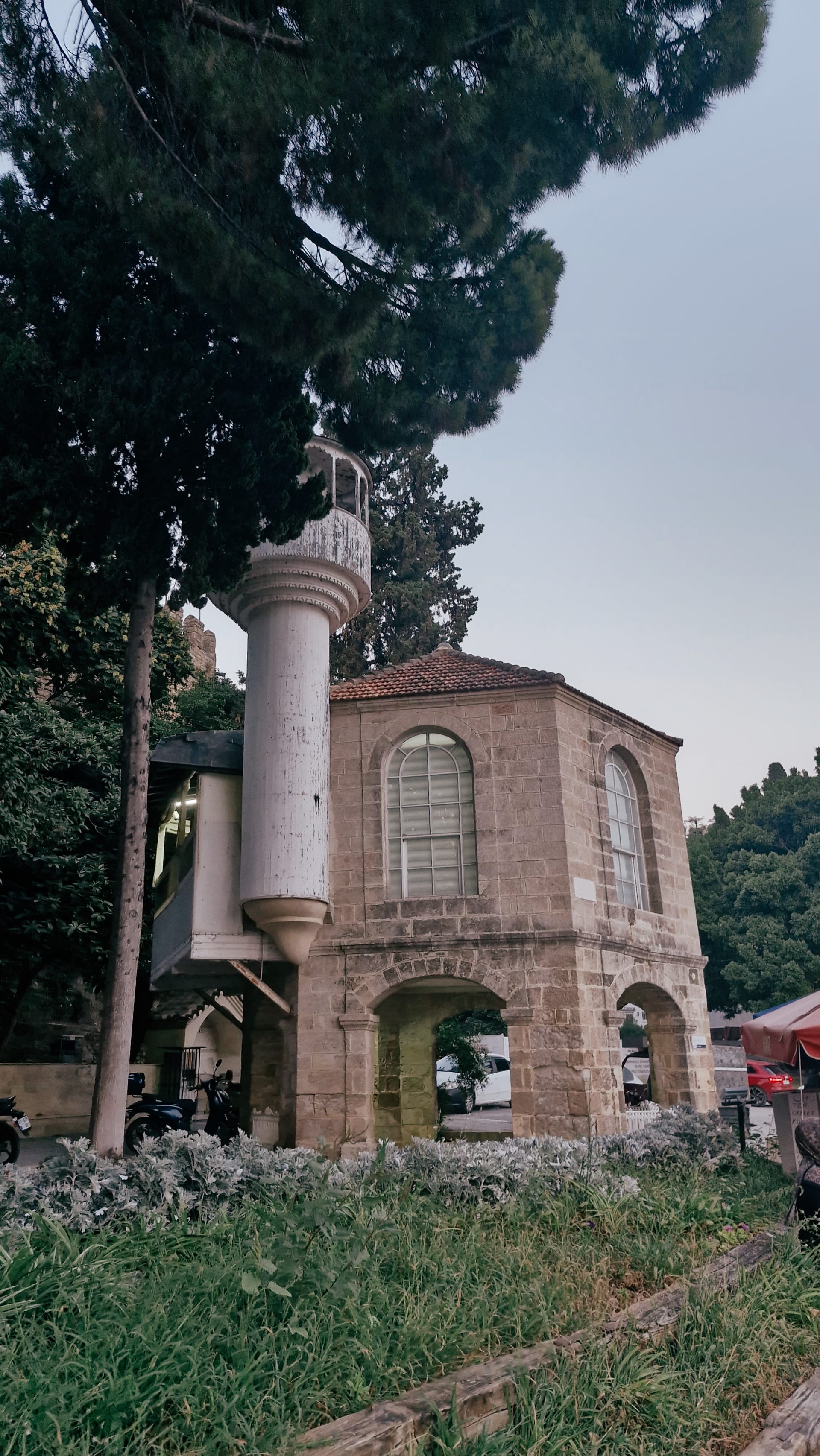 Small stone waterfront building with an arched opening and slender tower.