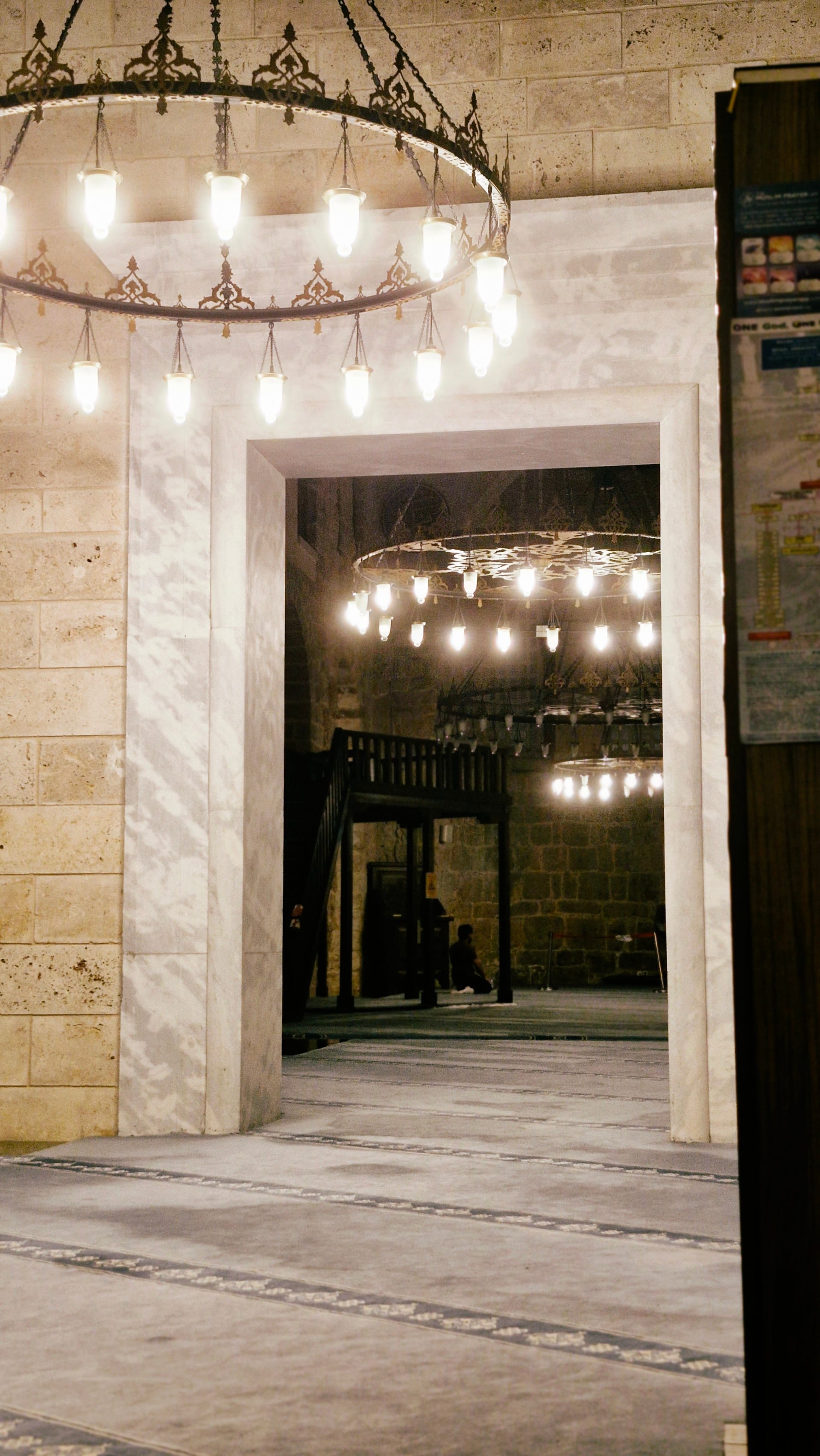 Stone doorway framing the softly lit interior and circular chandeliers beyond.