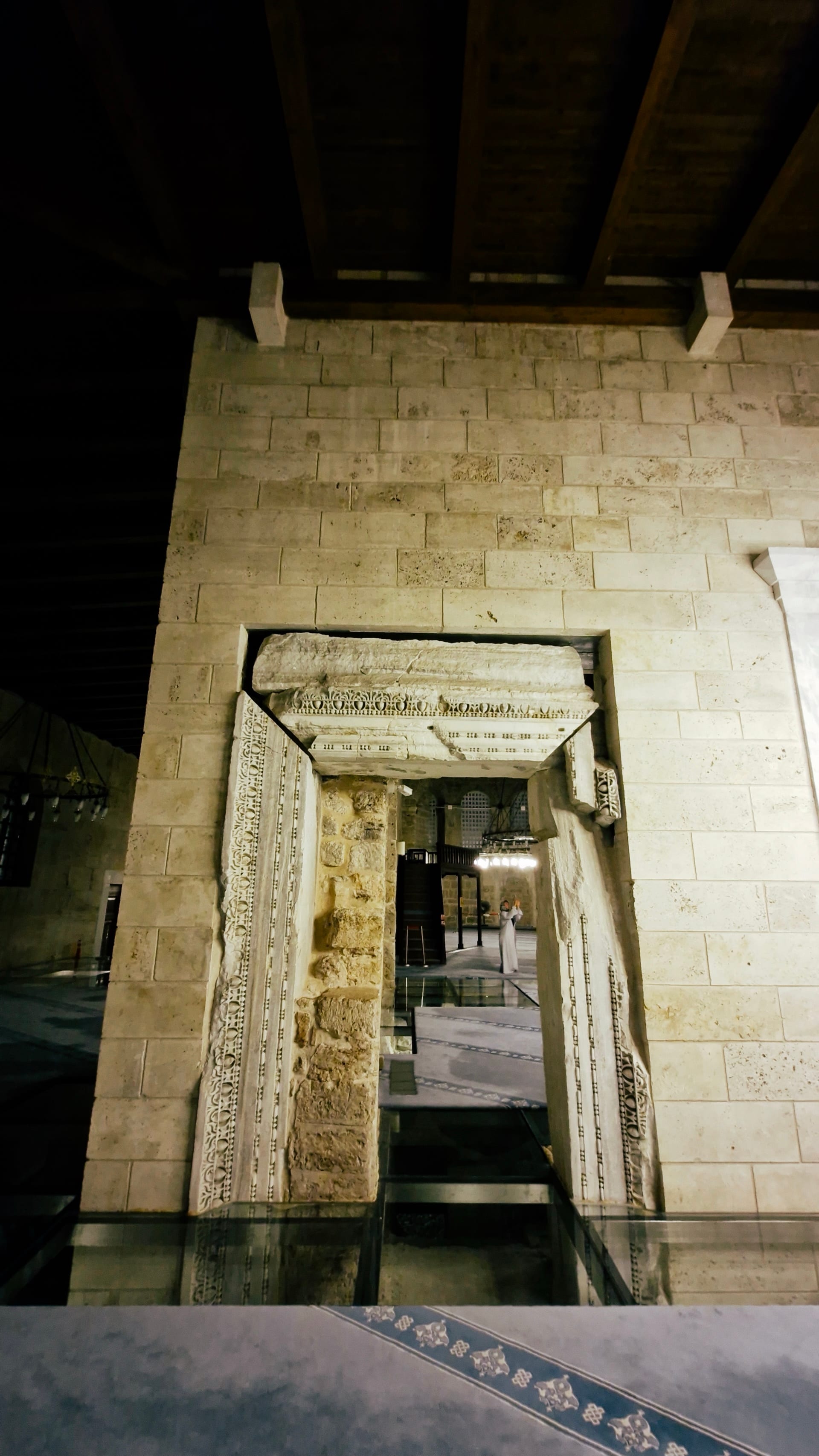 Ornately carved stone doorway framed by plain pale masonry.