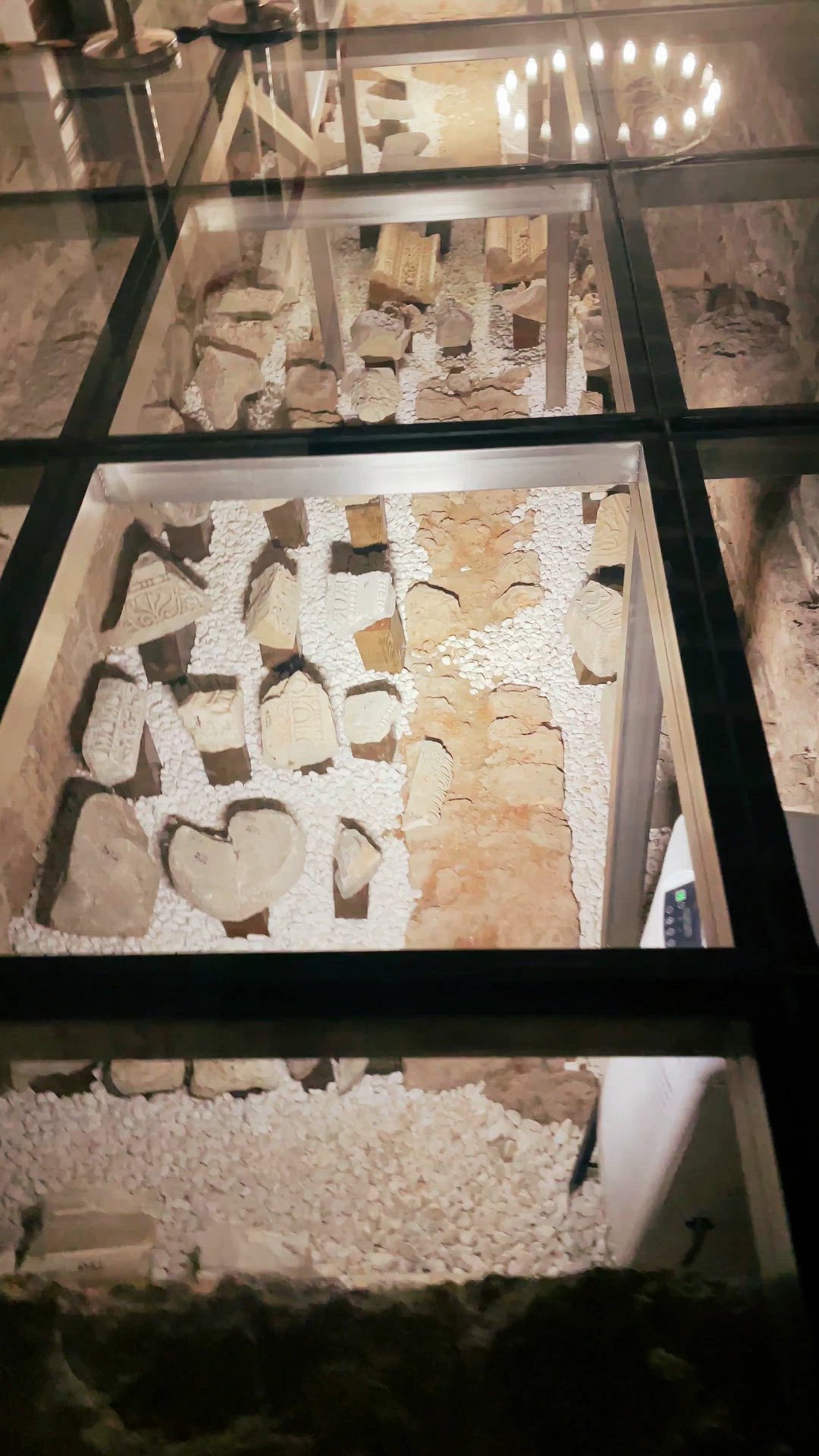 Video following glass-covered displays of carved and plain stone fragments.