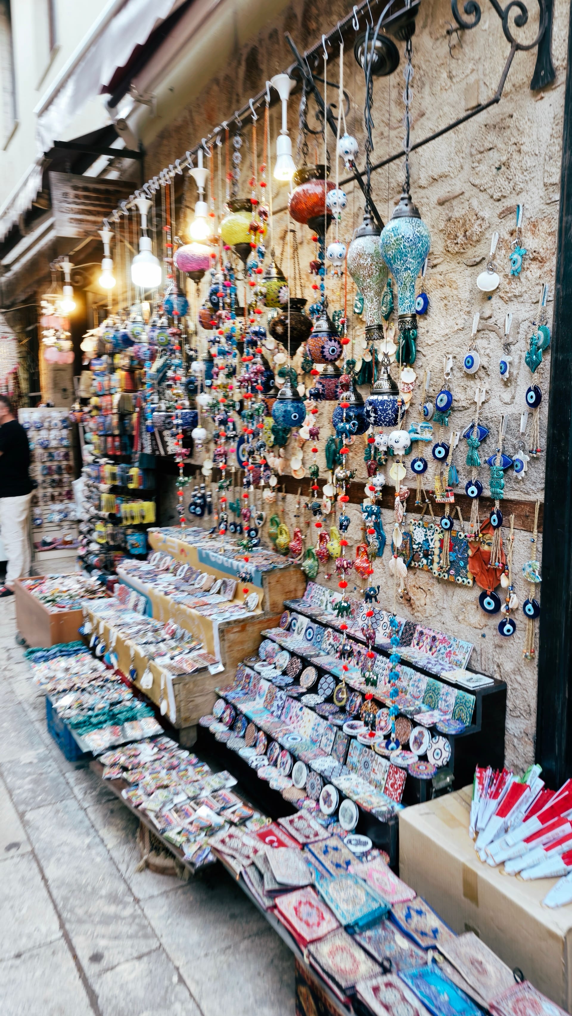 A stone-front shop displays blue evil-eye charms and colorful souvenirs.