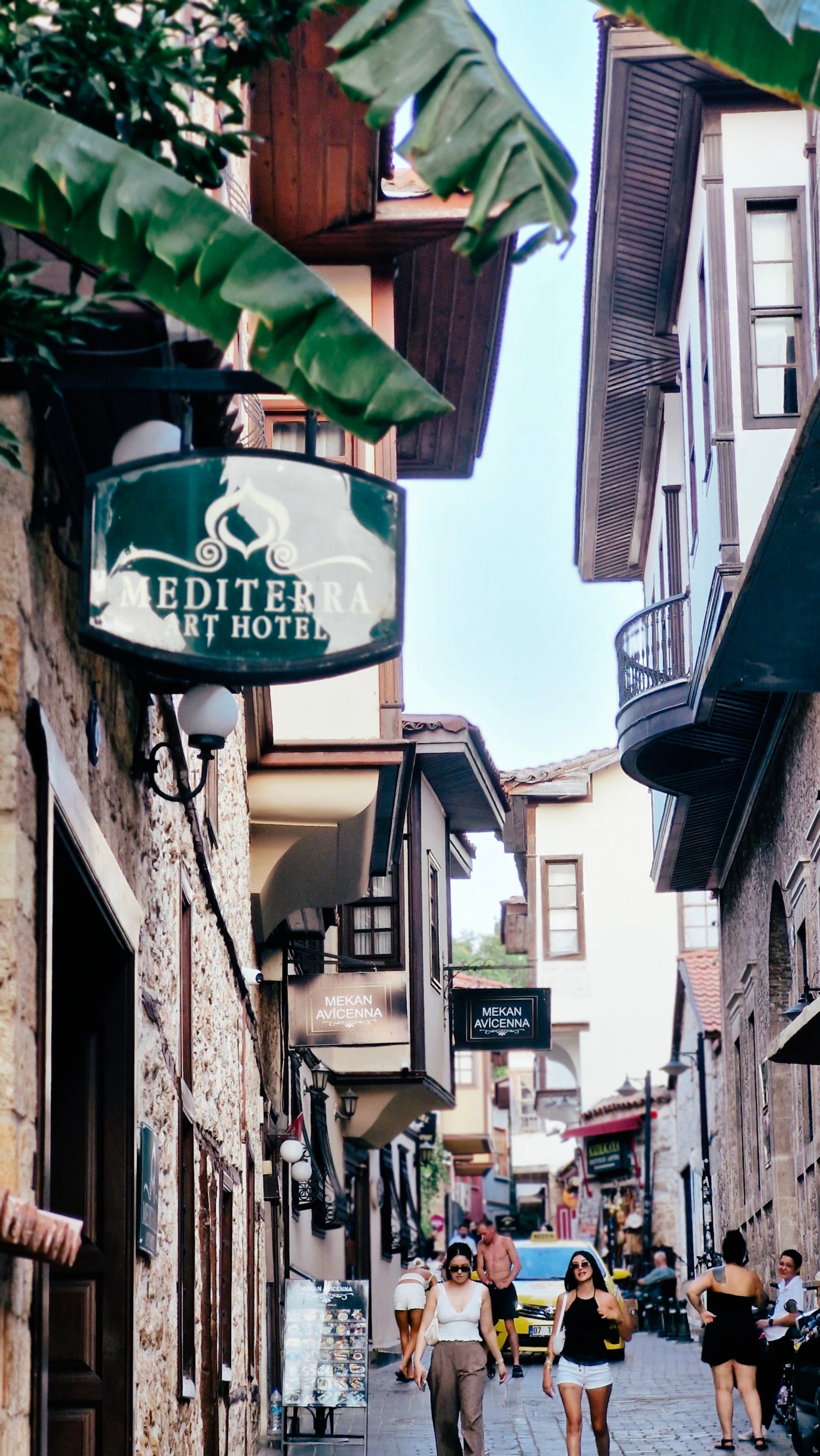 Hotel signs and timbered façades line a narrow street filled with pedestrians.