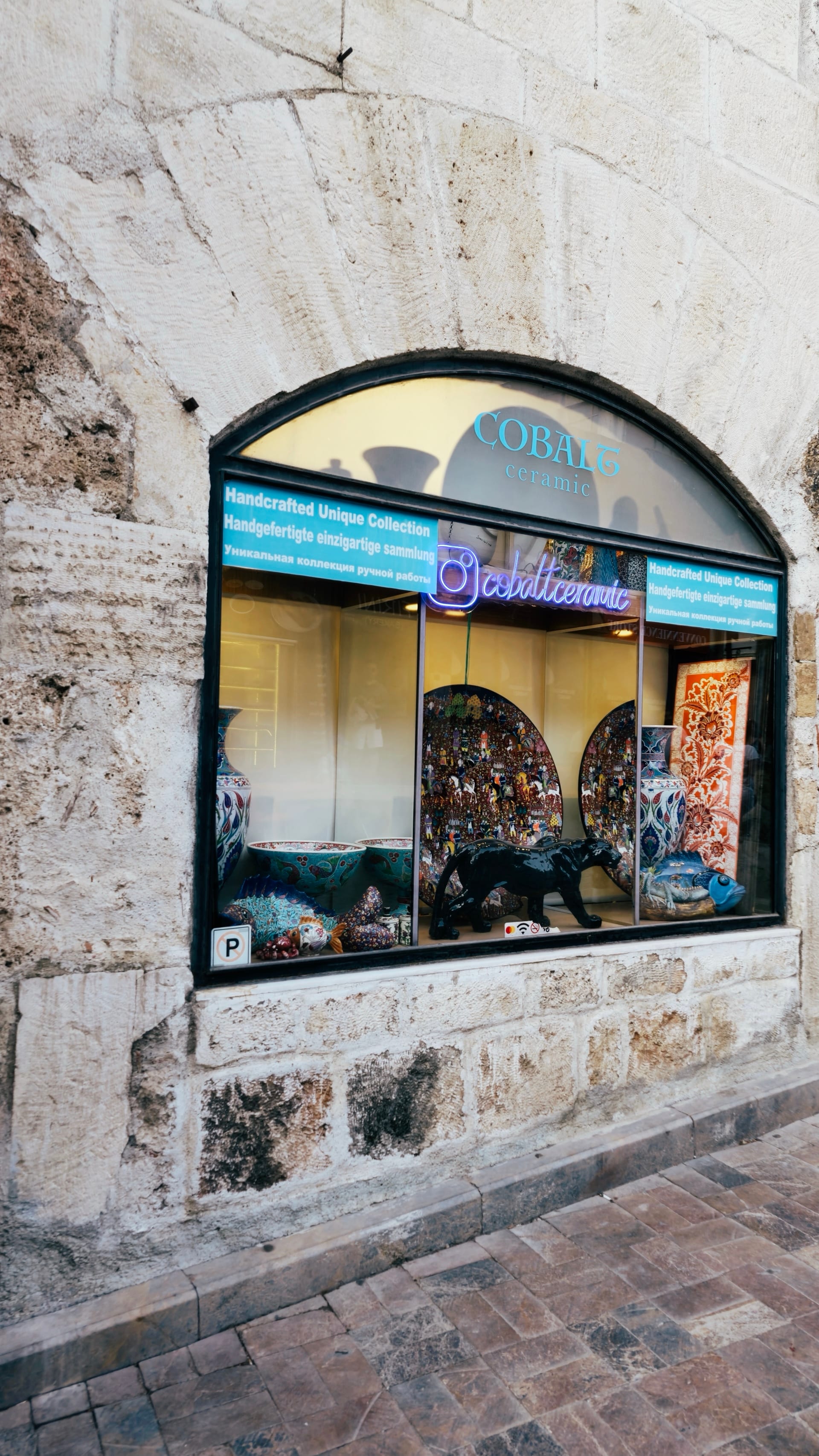 An arched shop window is set into a pale stone wall.