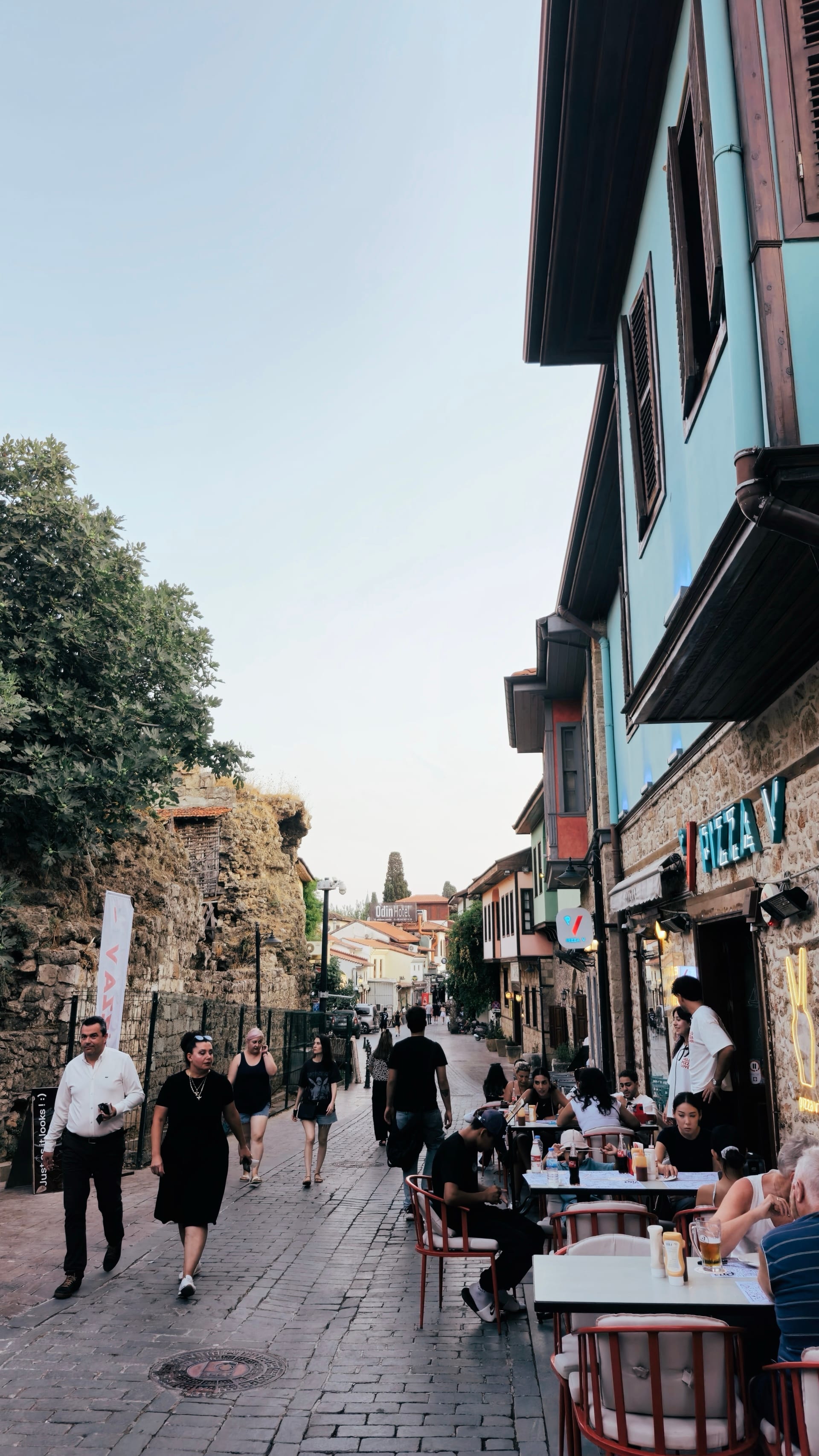 Café tables and pedestrians fill a lane bordered by stone and timbered buildings.