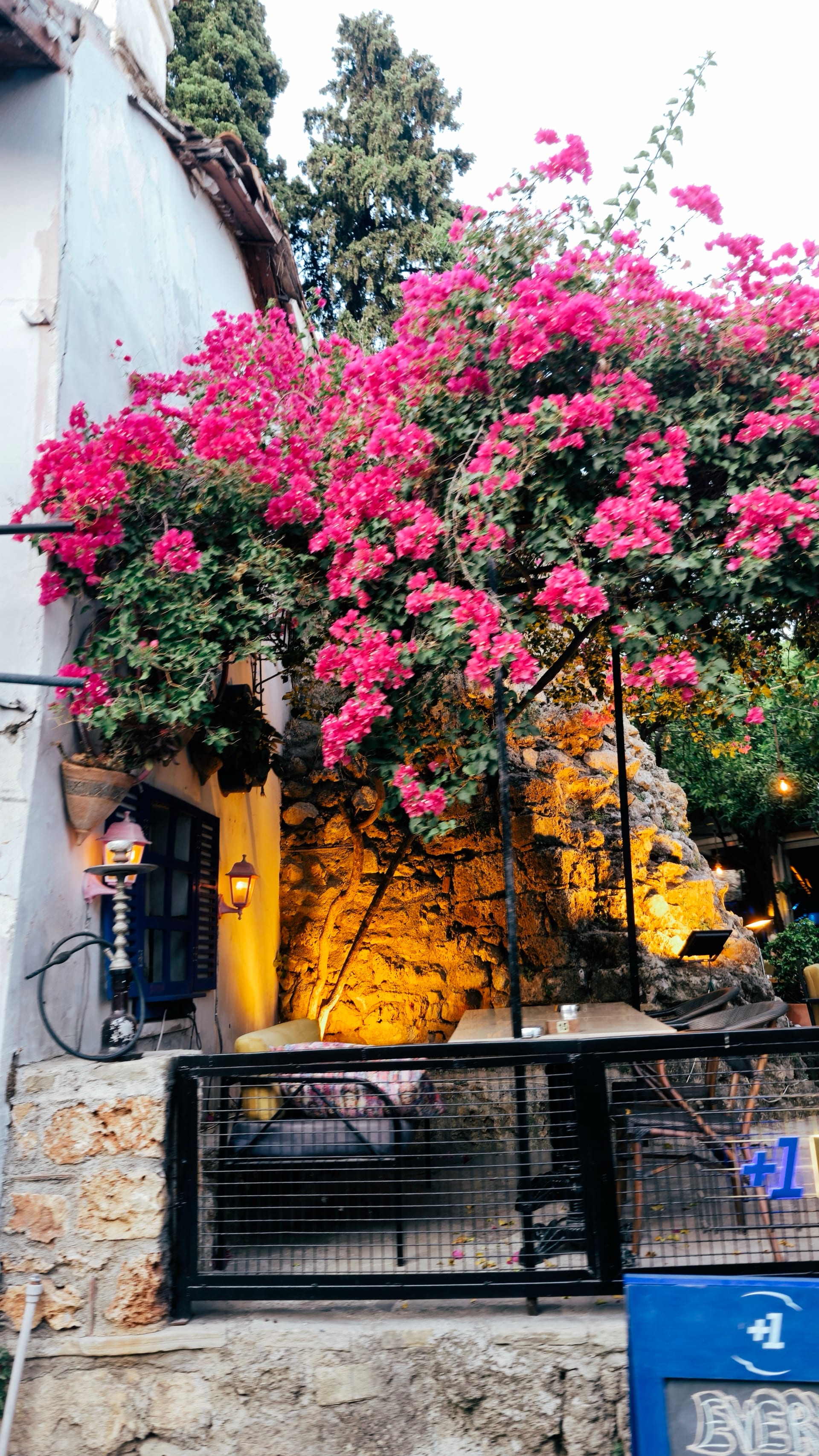 Pink bougainvillea covers a lit stone terrace above a narrow street.