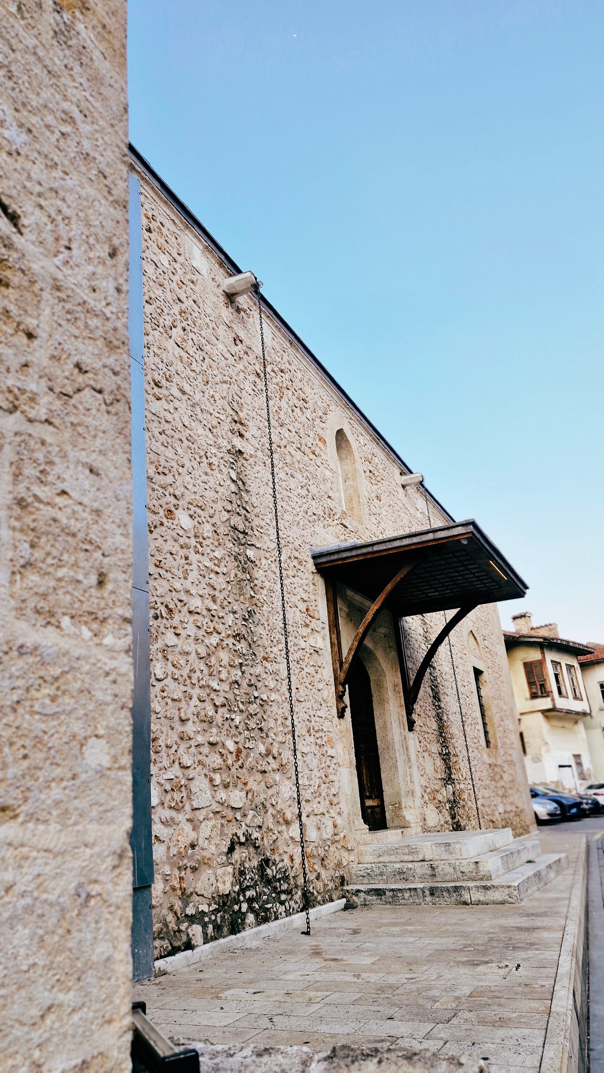 A long rough-stone wall with a projecting wooden awning borders the street.