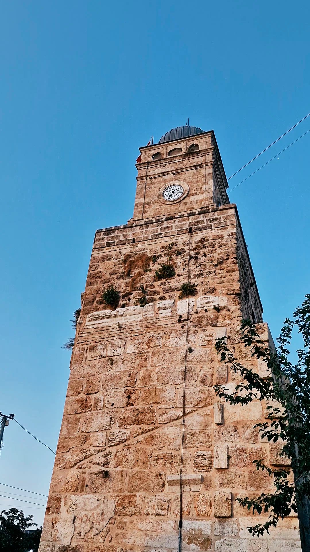 The stone clock tower fills the frame against a clear blue sky.